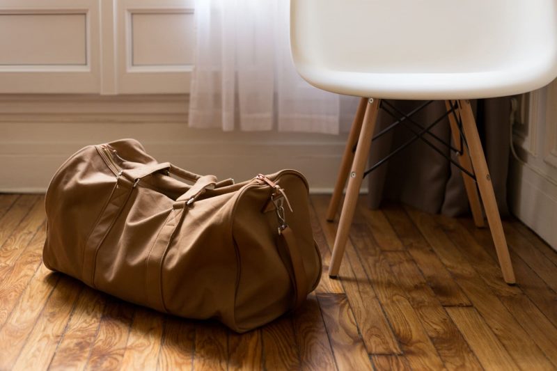 Brown duffel bag next to a white chair.
