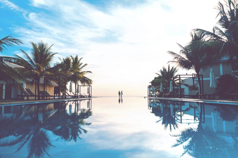 Ourdoor pool with reflection of the sky and palm trees