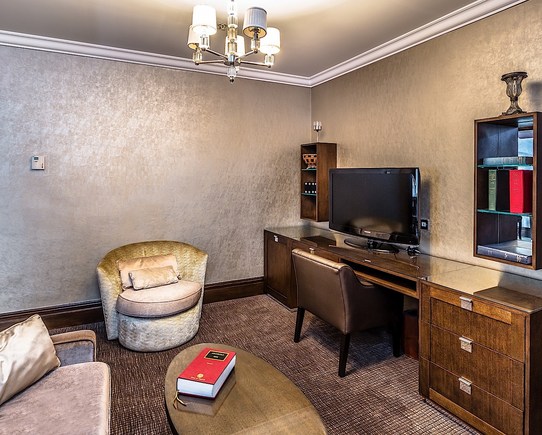 Suite room with comfortable chairs and a large desk with a TV.