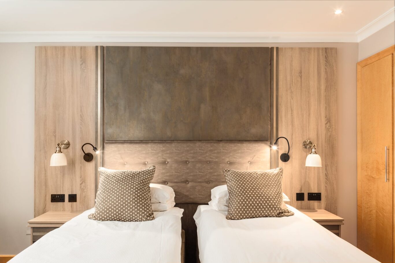 Twin bedroom with two single beds and grey headboard.