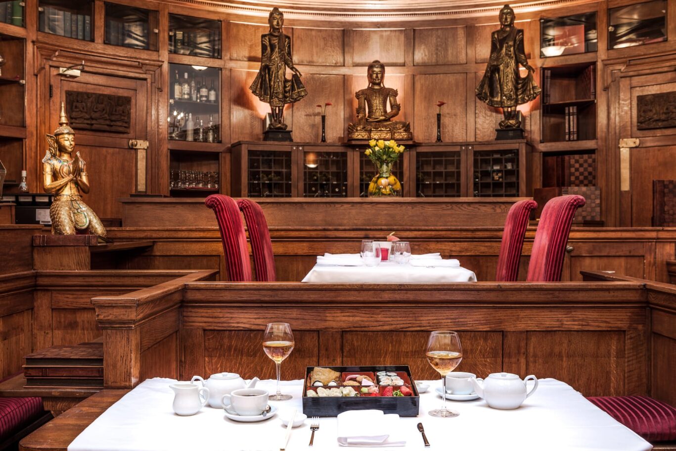 Silk restaurant with wood panelling, glasses of wine and sushi laid out.