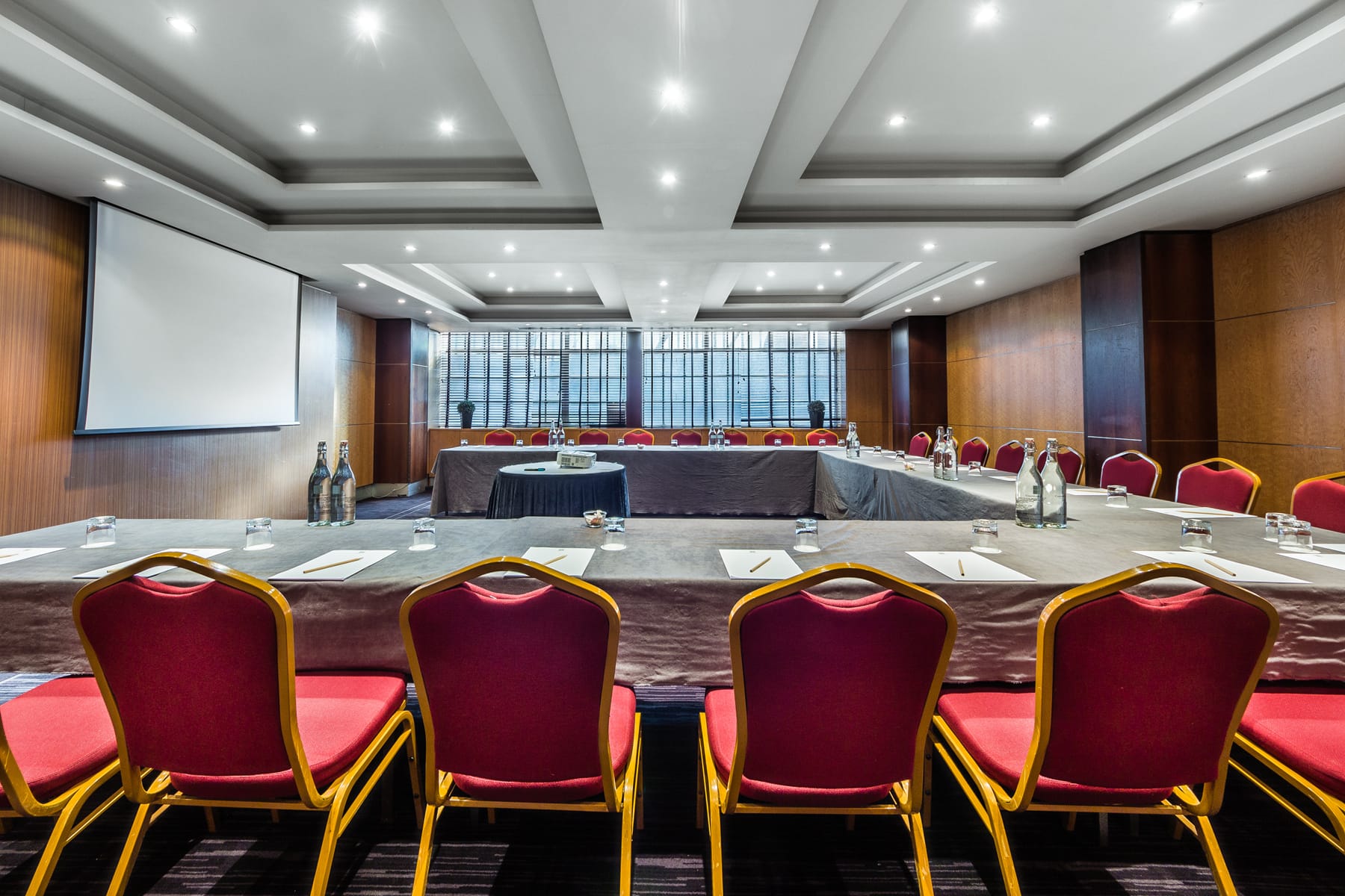 Large meeting room with a U-shaped table and red chairs.