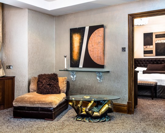 View of a suite room with a large comfy chair and glass side table
