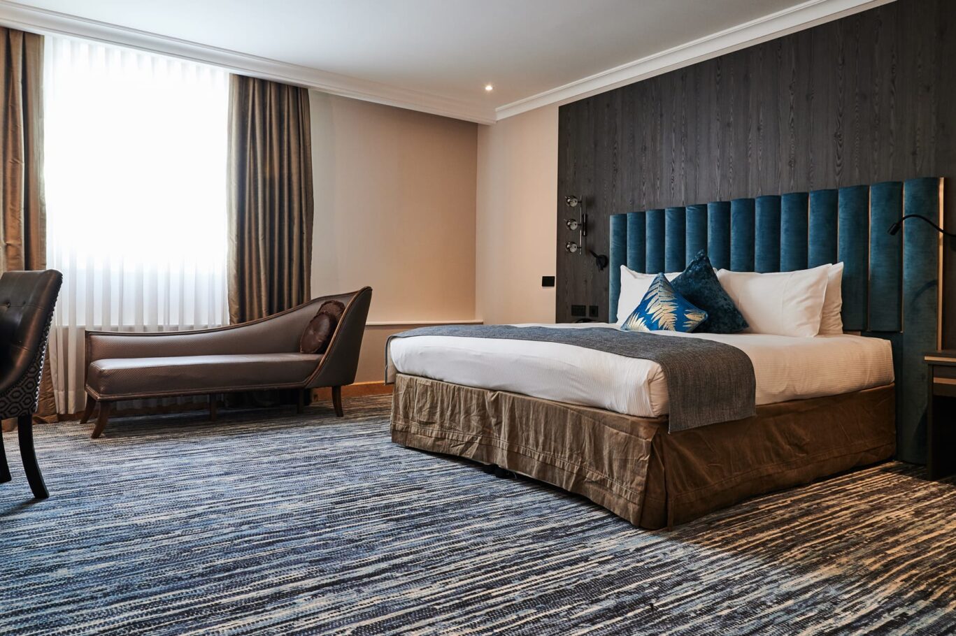 View of a large double room with chaise lounge sofa.