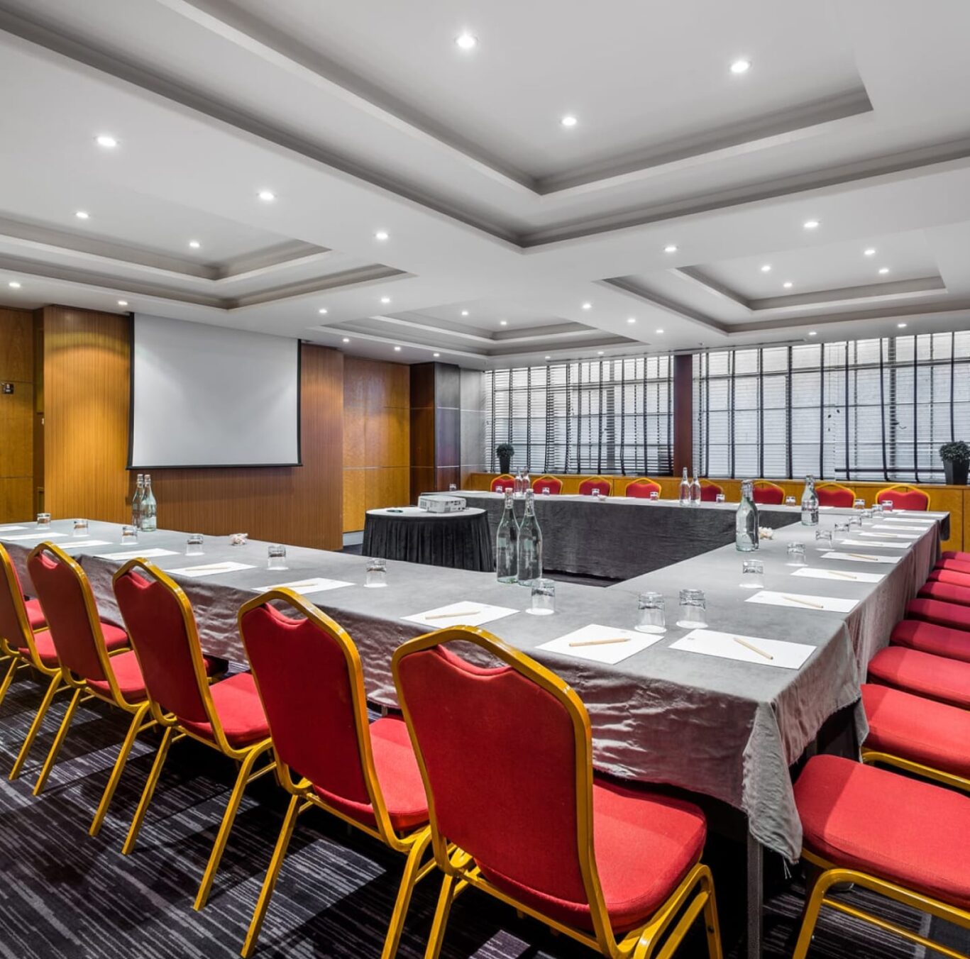 Large meeting room with U-shaped table and red chairs.