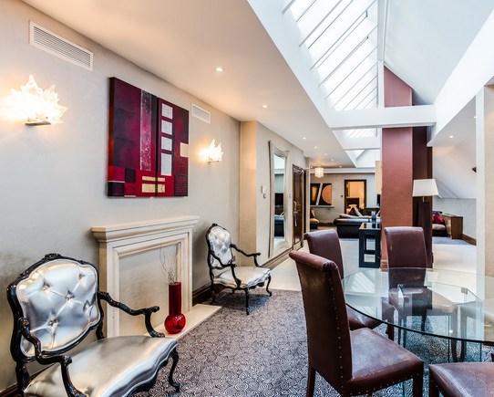 Dining area with leather chairs and a glass table, large roof windows.