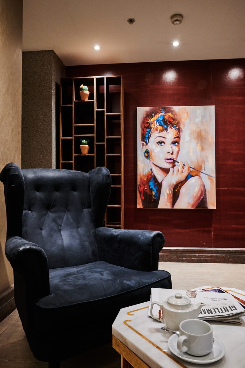 Seating area with large black chair and canvas artwork in the background.